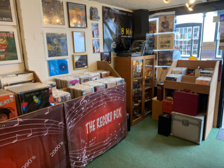 Back corner of the shop with framed artwork on the wall and a record-storage desk.