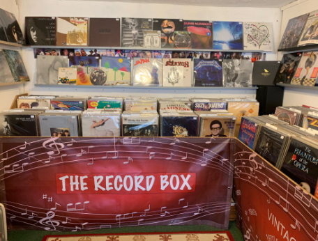 Record bins inside The Record Box with the shop's red 'The Record Box' banner across the front and an album-cover wall above.