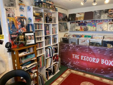 Inside the shop — tall bookshelves of CDs and books on the left, record bins and a patterned rug on the right.